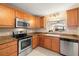 Well-lit kitchen featuring wood cabinetry, granite countertops, and stainless steel appliances at 7300 Sun Island S Dr # 605, South Pasadena, FL 33707