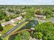 An aerial view showcasing a home next to a pond with a bridge, surrounded by lush greenery at 7633 Piping Rock Ct # 7633, New Port Richey, FL 34654