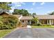 The single story home has a brown roof, a small front yard, and lots of trees at 7633 Piping Rock Ct # 7633, New Port Richey, FL 34654