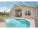 A kidney-shaped pool with a built-in rock waterfall, with seating and patio with ceiling fan at 8124 Brinegar Cir, Tampa, FL 33647