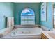 Inviting bathtub with jets under a large arched window showing clear blue skies and a serene water view at 8253 118Th Ave, Largo, FL 33773