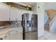 Kitchen with stainless steel refrigerator, white cabinets, decorative backsplash, and colorful stairs at 8253 118Th Ave, Largo, FL 33773