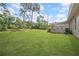Large backyard featuring a covered patio area, lush lawn, and mature trees in the background at 8433 101St Ave, Seminole, FL 33777