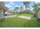 Expansive backyard with lush green grass, covered patio, and a wooded area in the distance at 8433 101St Ave, Seminole, FL 33777