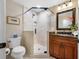 Bright bathroom featuring a glass shower, brown wood cabinet, and marble countertops at 903 Pinellas Bayway S # 103, Tierra Verde, FL 33715