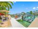 Waterfront dock with boat lift, outdoor seating, patio furniture, and lush tropical landscaping at 903 Pinellas Bayway S # 103, Tierra Verde, FL 33715