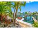 Beautiful waterfront dock with boat lift, outdoor seating, patio furniture, and lush tropical landscaping at 903 Pinellas Bayway S # 103, Tierra Verde, FL 33715