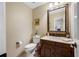 Charming powder room with dark wood vanity, marble countertop, and decorative mirror at 903 Pinellas Bayway S # 103, Tierra Verde, FL 33715