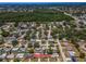 Aerial view of home in residential neighborhood, featuring a red tile roof and tree-lined streets near a green space at 9952 111Th St, Seminole, FL 33772