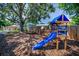 Spacious backyard featuring mature trees, a playset with a slide, picnic table and a partial basketball court at 9952 111Th St, Seminole, FL 33772