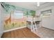 Bright bedroom with a playful mural, wooden floors, and a white bunk bed under a ceiling fan at 9952 111Th St, Seminole, FL 33772