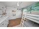 Cozy bedroom features wooden floors, white furniture, and a white bunk bed beneath a ceiling fan at 9952 111Th St, Seminole, FL 33772