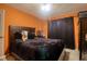 This bedroom features an orange accent wall, black curtains, dark wooden dressers and ceiling fan at 3234 Morven Dr, Spring Hill, FL 34609