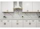 Elegant kitchen with white cabinets, marble backsplash, and sleek range hood at 11508 Sage Canyon Dr, Riverview, FL 33578