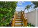Wooden stairway leading to a pool area, flanked by lush greenery and a white fence at 11746 93Rd Ave, Seminole, FL 33772