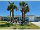 Charming home featuring light-blue siding, a well-manicured lawn, and beautiful landscaping with palm trees at 12300 4Th E St, Treasure Island, FL 33706