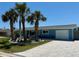Charming home featuring light-blue siding, a well-manicured lawn, and beautiful landscaping with palm trees at 12300 4Th E St, Treasure Island, FL 33706