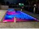 In-ground pool and hot tub with vibrant lighting, offering a perfect outdoor oasis for relaxation and entertainment at 12300 4Th E St, Treasure Island, FL 33706