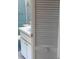 Compact bathroom with vanity, toilet, and a tiled shower behind slatted door at 12801 Winding Way, Hudson, FL 34667