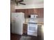 A kitchen featuring a white stove and refrigerator, complemented by brown cabinets at 12801 Winding Way, Hudson, FL 34667