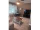 Cozy living room features a ceiling fan, window, lamp, coffee table and television set in a neutral color scheme at 12801 Winding Way, Hudson, FL 34667