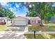 Charming single-story home with a well-maintained lawn, mature tree, and an attached two-car garage at 12910 Leadwood Dr, Riverview, FL 33579