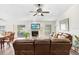 Bright living room featuring a ceiling fan, fireplace, leather furniture, and sliding glass doors to the backyard at 12910 Leadwood Dr, Riverview, FL 33579