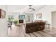 Bright living room featuring a ceiling fan, fireplace, leather furniture, and sliding glass doors to the backyard at 12910 Leadwood Dr, Riverview, FL 33579