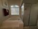 Bright bathroom featuring a glass-enclosed shower, soaking tub, and arched window at 13133 Roseanna Dr, Spring Hill, FL 34609