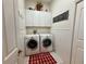 Bright laundry room featuring white cabinets, wainscoting, and red accents for a clean and organized space at 13133 Roseanna Dr, Spring Hill, FL 34609