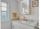 Bright bathroom featuring white marble countertops, modern fixtures, and a lighted mirror at 134 W Saint Annes Cir, Apollo Beach, FL 33572