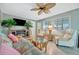 Bright living room with ceiling fan, rattan furniture, television, and leafy plants at 134 W Saint Annes Cir, Apollo Beach, FL 33572