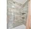 Shower featuring marble tile, a shower head, grab bar and built-in shelves at 134 W Saint Annes Cir, Apollo Beach, FL 33572