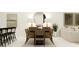 Modern dining room with a black wood table, six woven chairs, a round mirror, and decorative lamps at 13530 White Gold Run, Parrish, FL 34219