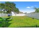 Large backyard enclosed by a white fence, complemented by green grass and mature trees for outdoor enjoyment at 13765 Whiskey Daisy Dr, Dade City, FL 33525
