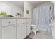 Well-lit bathroom with a vanity, decorative shower curtain, toilet, and tile flooring at 13765 Whiskey Daisy Dr, Dade City, FL 33525