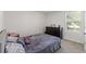 Cozy bedroom featuring a queen-size bed, dresser, and a bright window with blinds offering natural light at 13765 Whiskey Daisy Dr, Dade City, FL 33525