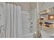 Clean bathroom featuring a shower/tub combo, white shower curtain, and a three-tiered shelving unit for storage at 1398 Crescent Hoop Way, Wesley Chapel, FL 33543