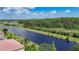 Breathtaking view of a canal and green space, with backyard featuring lush trees and tropical plants at 15860 Aurora Lake Cir, Wimauma, FL 33598