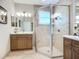 Bathroom showcasing a tiled walk-in shower with glass doors and a vanity with wooden cabinets at 15860 Aurora Lake Cir, Wimauma, FL 33598