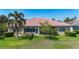 Back exterior view of home with a red tile roof and lush landscaping at 15860 Aurora Lake Cir, Wimauma, FL 33598