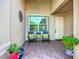 Cozy front porch features a seating area and potted plants on a brick-paved surface at 15860 Aurora Lake Cir, Wimauma, FL 33598