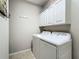 White washer and dryer with overhead cabinets in a well lit laundry room at 15860 Aurora Lake Cir, Wimauma, FL 33598