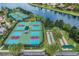 Aerial view of well-maintained pickleball and shuffleboard courts next to a scenic lake in a vibrant community at 15860 Aurora Lake Cir, Wimauma, FL 33598