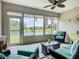 Enclosed sunroom with ample seating, peaceful lake views, and ceiling fan at 15860 Aurora Lake Cir, Wimauma, FL 33598