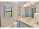 Well-lit bathroom featuring a gray vanity, a large mirror, and a window with natural light at 1806 Powder Ridge Dr, Valrico, FL 33594