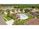 Aerial view of a community pool surrounded by green lawns and trees with chairs and a pool house at 26338 Whirlaway Ter, Wesley Chapel, FL 33544