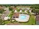 Aerial view of a community pool surrounded by green lawns and trees with chairs and a pool house at 26338 Whirlaway Ter, Wesley Chapel, FL 33544