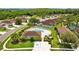 Aerial view of a community pool surrounded by green lawns and trees with chairs and a pool house at 26338 Whirlaway Ter, Wesley Chapel, FL 33544