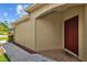 The home's red front door adds a touch of warmth and curb appeal to the exterior at 26338 Whirlaway Ter, Wesley Chapel, FL 33544